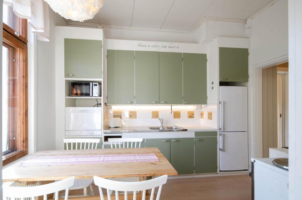 a kitchen with green cabinets and a wooden table and chairs at Studio Skata in Pietarsaari