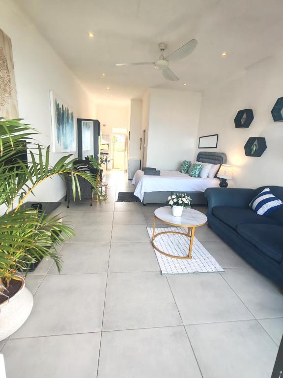 a living room with a blue couch and a bed at Aloe Shore- Whale Watch from Balcony- Stunning in Umdloti