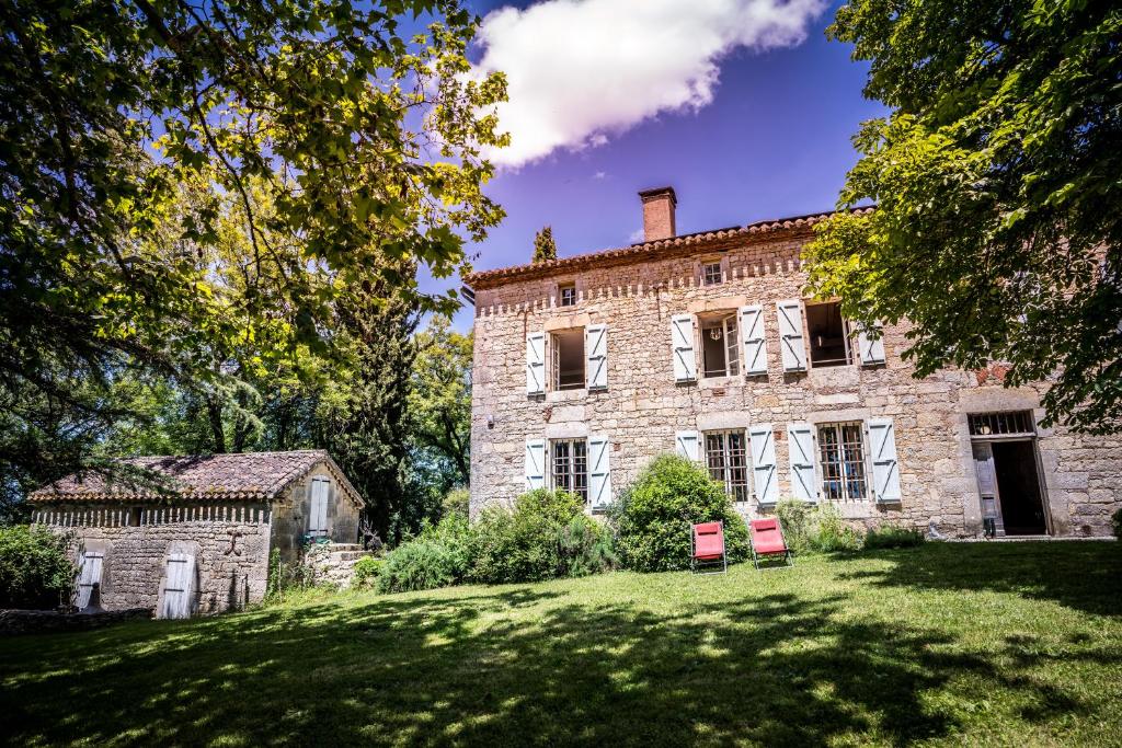 an old stone house with two red chairs in the yard at Les Hauts de Sauliès - Chambre et Table d'Hôtes de charme in Vers