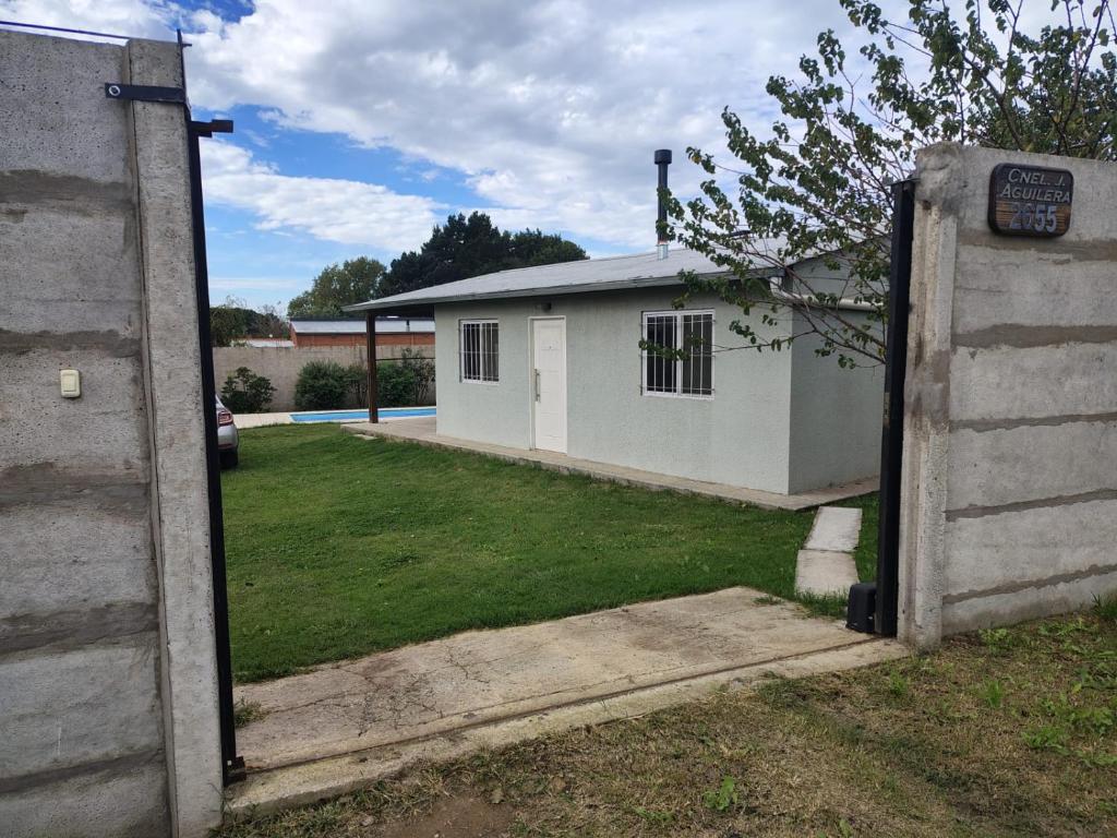 a gate to a white house in a yard at El último Cartucho in Tandil