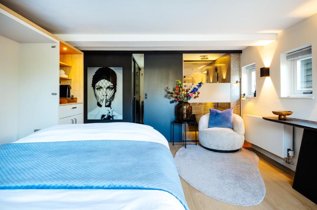 a bedroom with a large bed and a chair at La petite chambre in Bennekom
