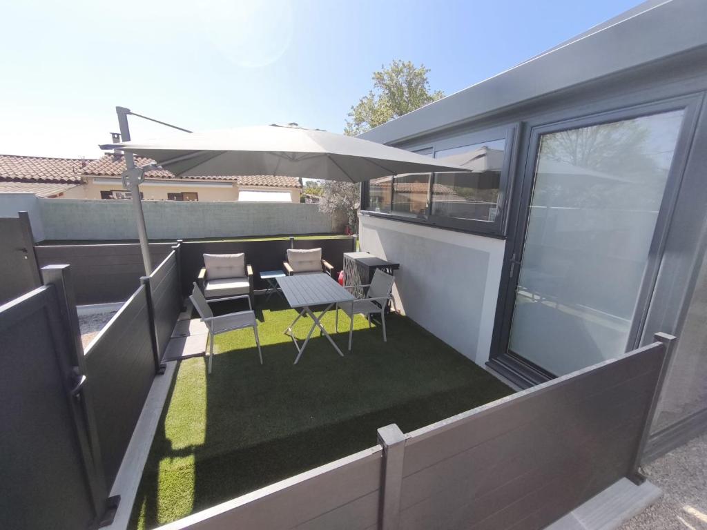 a balcony with an umbrella and a table and chairs at Charmant Studio in La Motte-dʼAigues