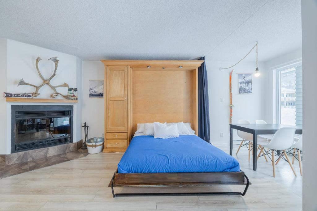 a bedroom with a bed and a table and a fireplace at Le loft du Hameau in Stoneham