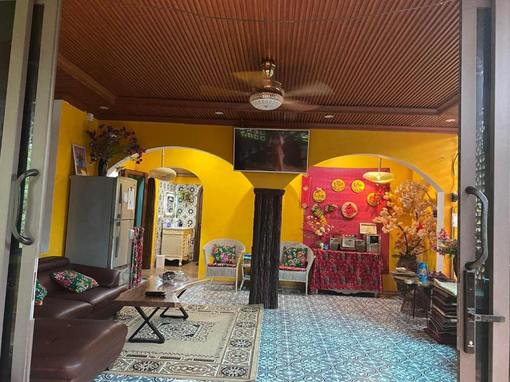 a living room with yellow walls and a couch and chairs at Nhà Bên Suối Retreat in Làng Tè