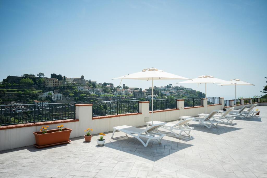 a row of white chairs and umbrellas on a roof at Guesthouse with Suites on the Amalfi Coast - Residence Villa Ruocco near Amalfi - 300sqm Open Terrace near Ravello - Breathtaking View in Scala
