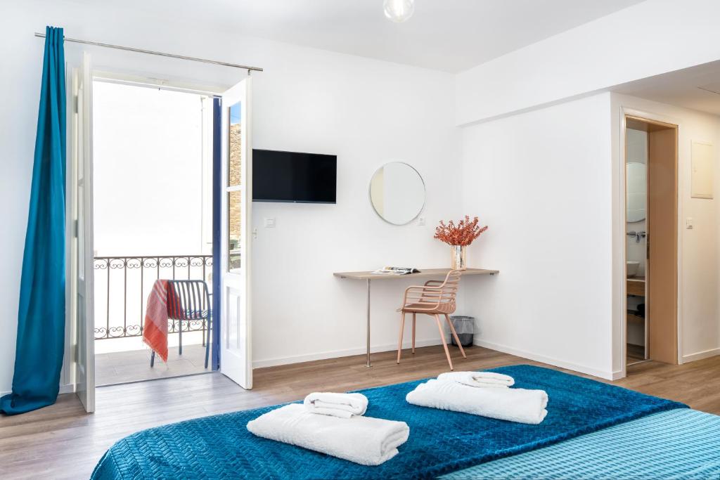 a white room with a blue bed and a desk at Twelve 12 Islands in Symi