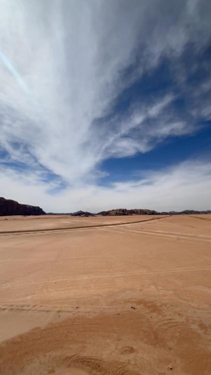 an empty desert with a blue sky and clouds at وادي رم مخيم عادل in Wadi Rum
