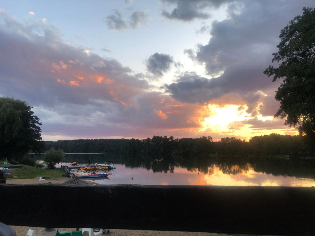 a sunset over a lake with boats on it at Joyosada - Ferienhäuser in Seenlandschaft in Prusim