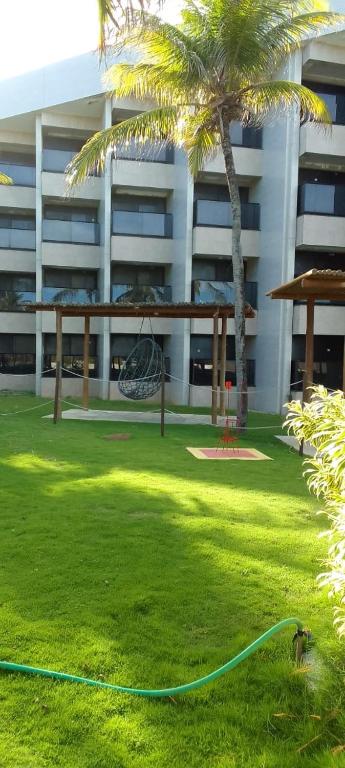 a hammock hanging from a palm tree in front of a building at Hotel Pirâmides natal in Natal