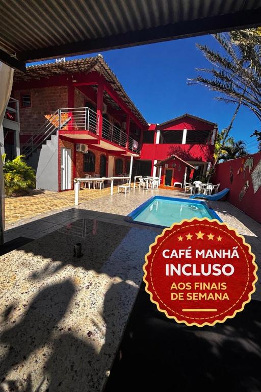 a house with a sign in front of a swimming pool at Pousada N'ativaMar in Guaratuba