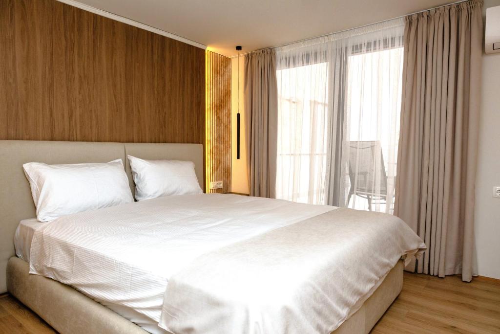 a bedroom with a white bed and a large window at ZARO Apartments in Bitola