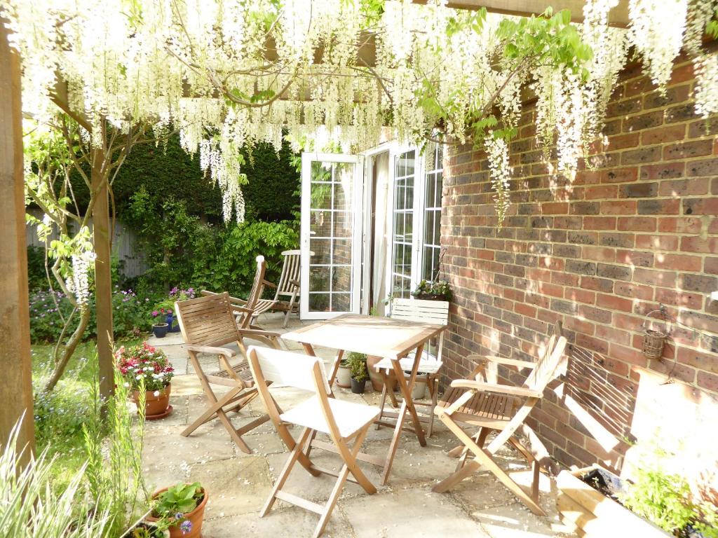 a patio with a table and chairs and a brick wall at Wisteria House in Blean