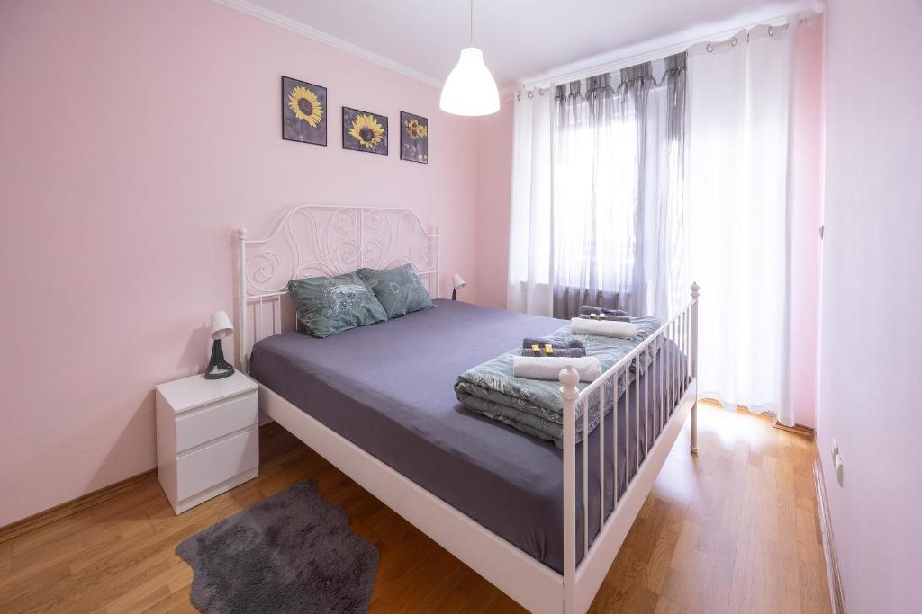 a bedroom with a white bed and a crib at Apartment Sunflower021 in Novi Sad
