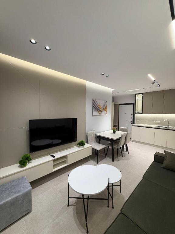 a living room with a couch and tables and a tv at Sako Apartaments 2 in Golem