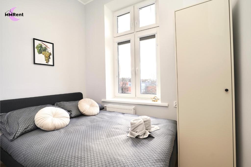 a bedroom with a bed with pillows and a window at MMRent Grape Room in Gdańsk