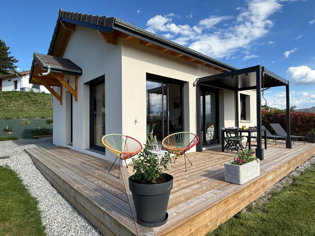 a house with a deck with chairs and a table at The Nest - cosy chalet for two in Jarjayes