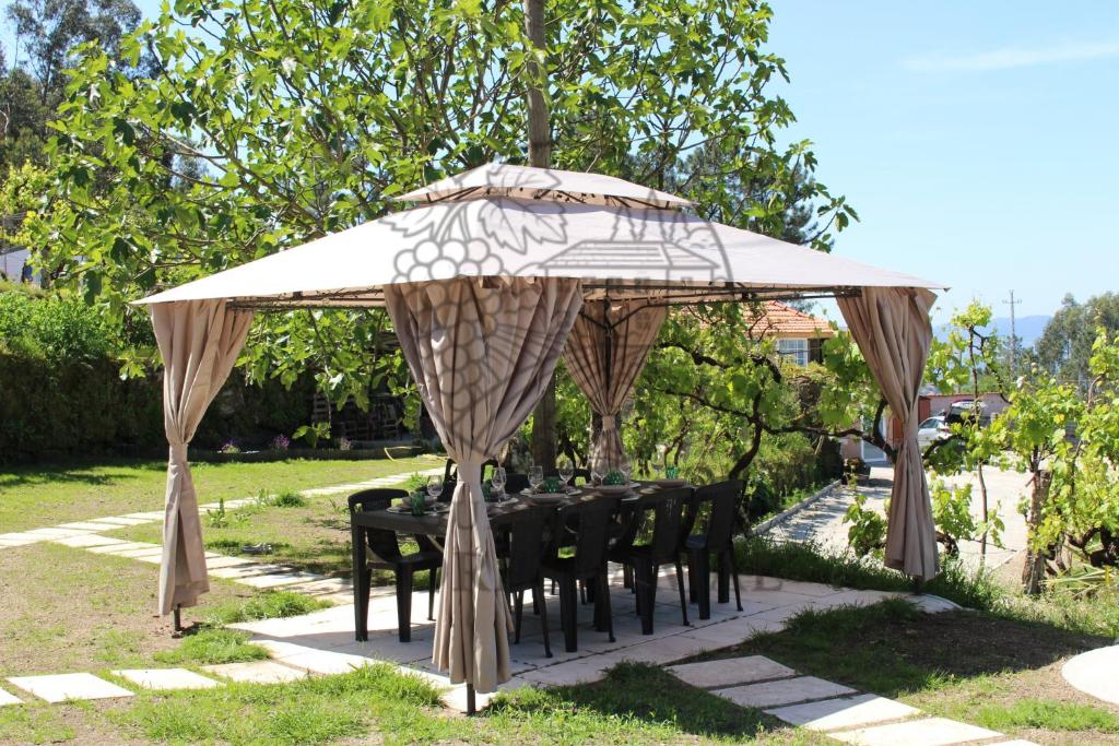 a table under a canopy with black tables and chairs at Quinta das Flores da Mãe in Folhada