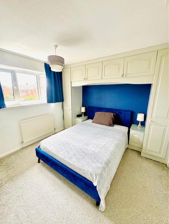 a bedroom with a large bed with a blue headboard at Unnati stay in Buckinghamshire