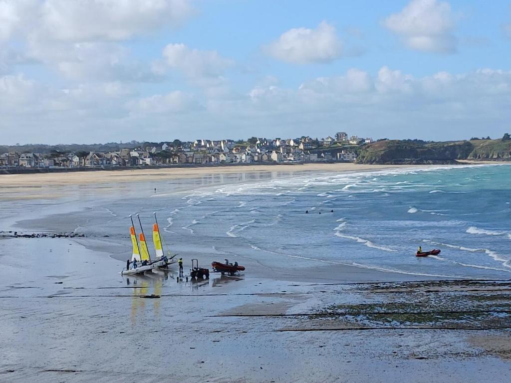 two boats sitting on a beach with the ocean at Studio très belle vue mer in Pléneuf-Val-André