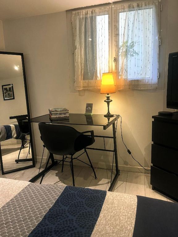 ein Schlafzimmer mit Schreibtisch mit Lampe und Bett in der Unterkunft Studio Bx Métropole Eysines A côté du tram in Eysines