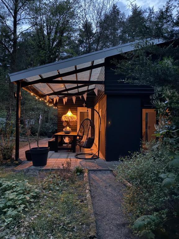 a pergola with a table in a garden at Dromen op 1 - Stijlvol boshuis op de Veluwe met veranda en grote omheinde tuin! in Nunspeet