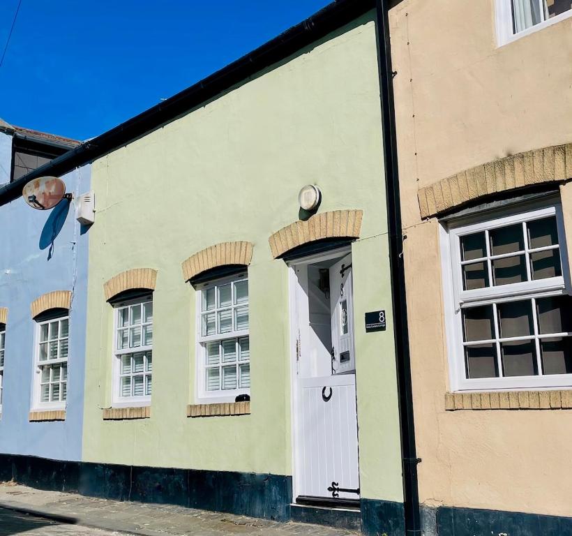 a green building with a white door and windows at Cosy Coastal Cottage in Tynemouth