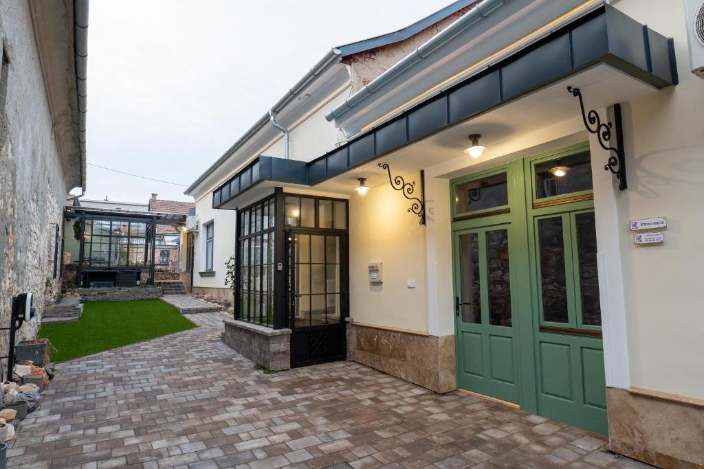 a building with green doors and a brick walkway at Kispolgár Vendégház in Sárospatak