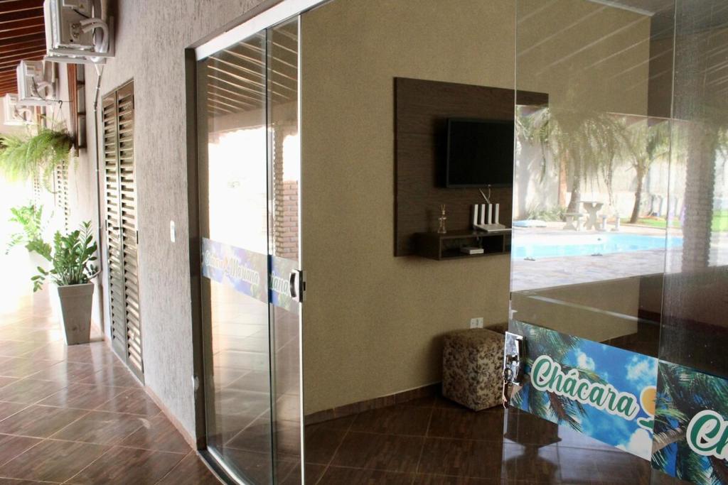 a glass shower door in a room with a pool at Chacara Mariana in Olímpia