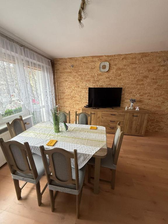 a dining room with a table and chairs and a television at Apartament MIRO in Ostróda