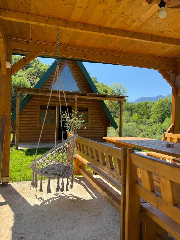 a porch swing in front of a log cabin at AI Cottage in Virpazar