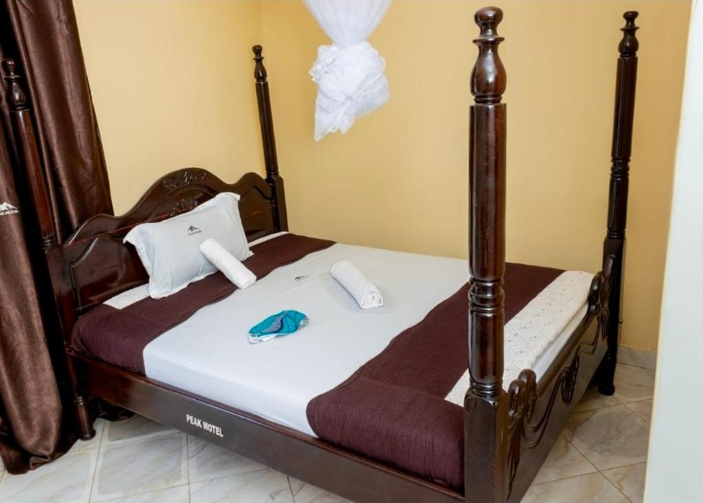 a bedroom with a bed with a wooden frame at Peak Motel in Kasese