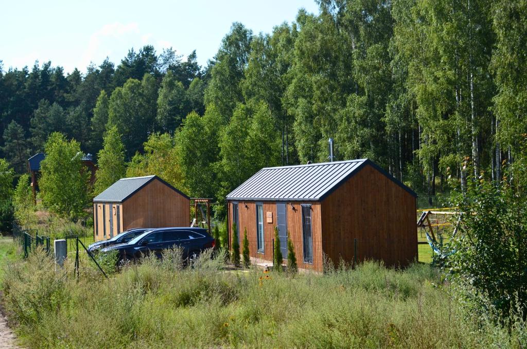 a car parked in front of two small buildings at Ostoja Wycinki domki letniskowe in Jaszczerz