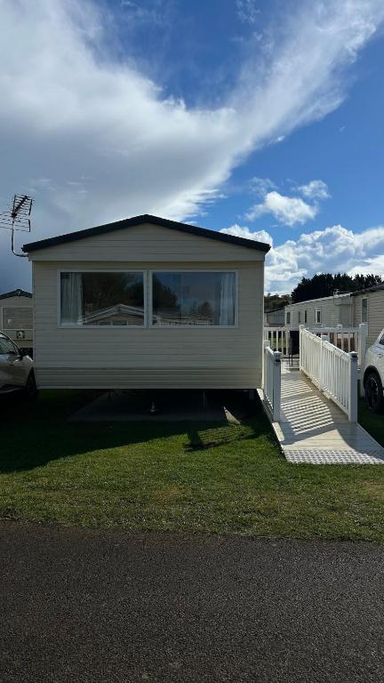 a small white house with a porch and a yard at Crichtons Caravan at Haven Seton Sands in Port Seton