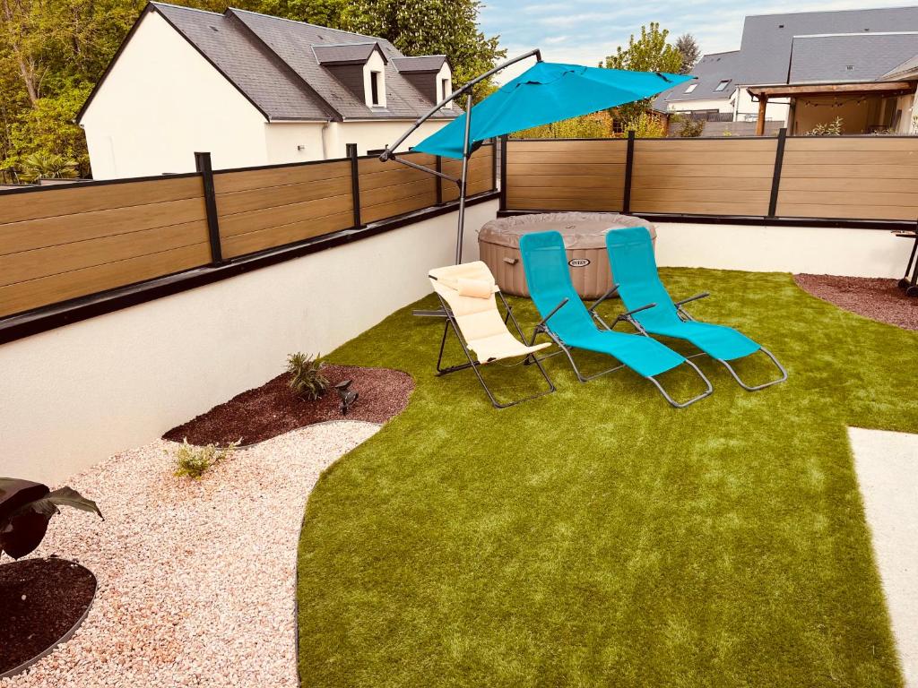 two chairs and an umbrella on a lawn at Maison moderne 3 chambres SPA-jacuzzi mai-septembre in Cerelles