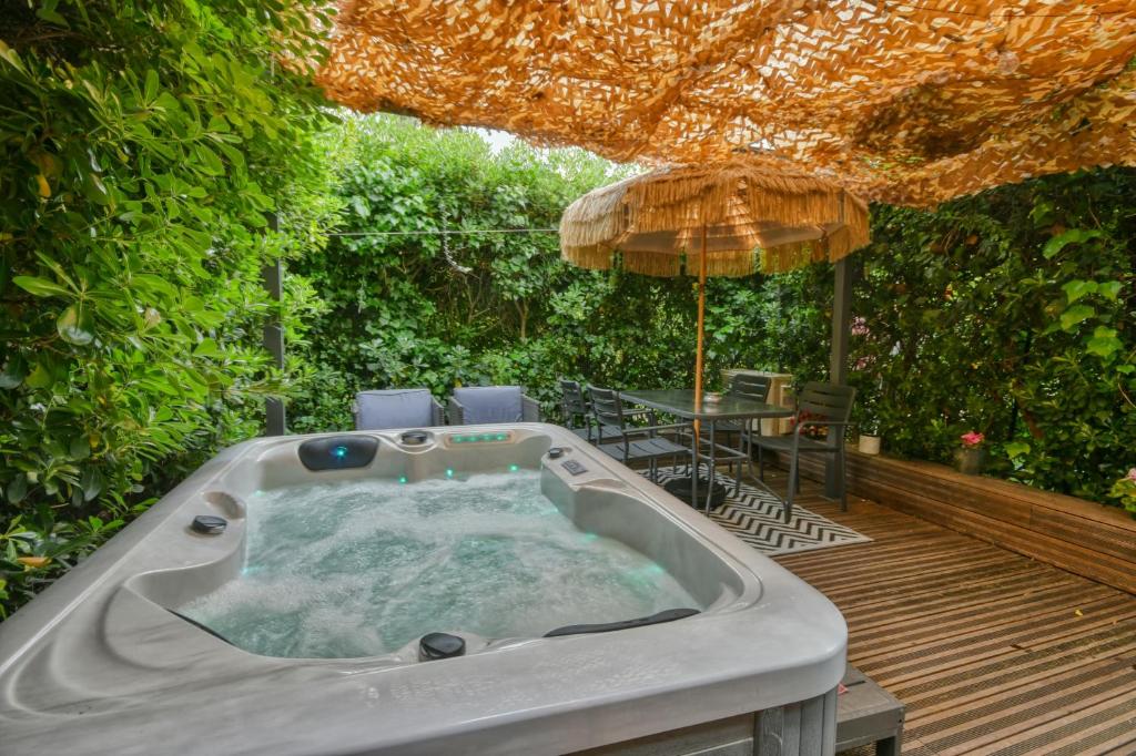 a hot tub on a deck with an umbrella at The Beach Dream in Saint-Laurent-du-Var