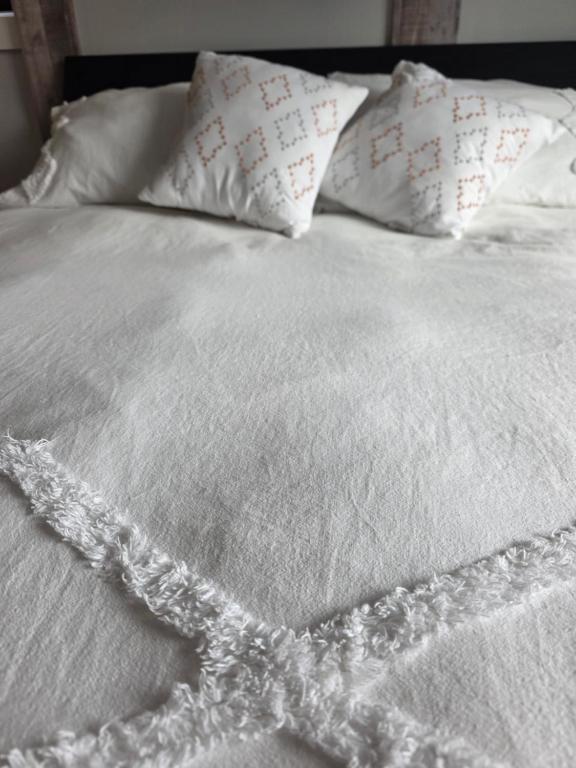 a white bed with white sheets and pillows at Endless Summer in Summerland