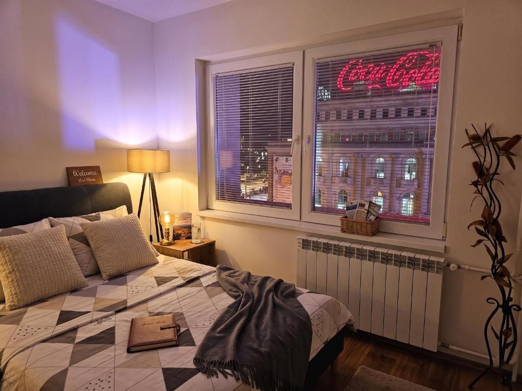 a bedroom with a bed and a window with a neon sign at Prime Main Square Location in Skopje
