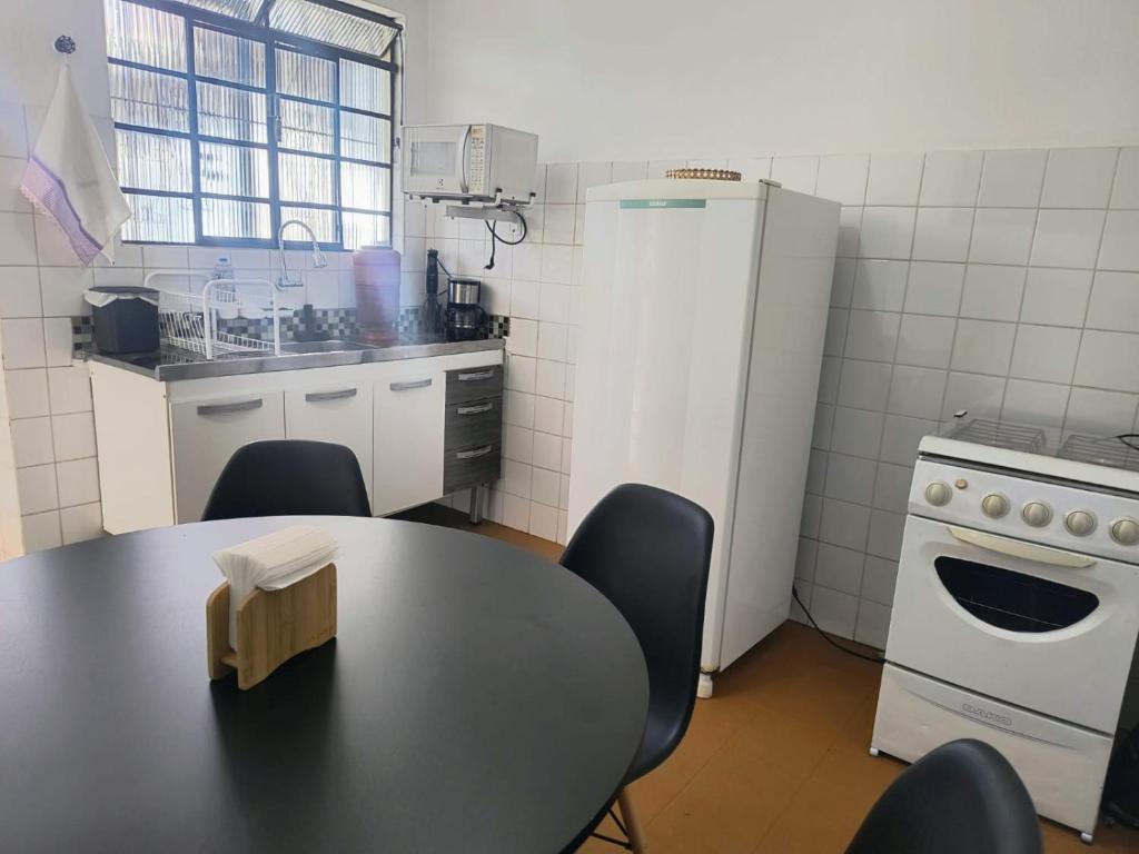 a kitchen with a table and a white refrigerator at Espaço Meditare in Socorro