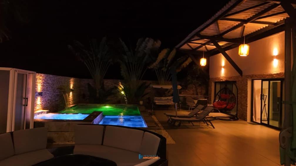 a patio at night with a pool and chairs at villa km22 in Assinie