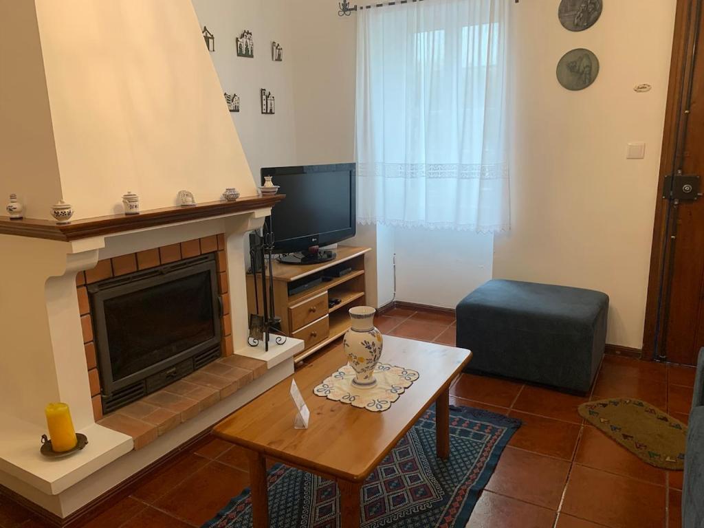 a living room with a fireplace and a tv at Charming Blue House in Furnas