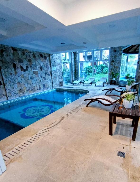 a large swimming pool in a house with a table at Haras del Bosque in Mar de las Pampas