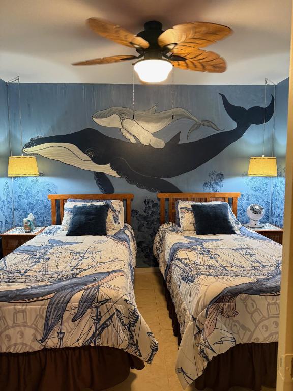 a bedroom with two beds and a ceiling fan at Unique Artist Home Steps from the Ocean in Kihei