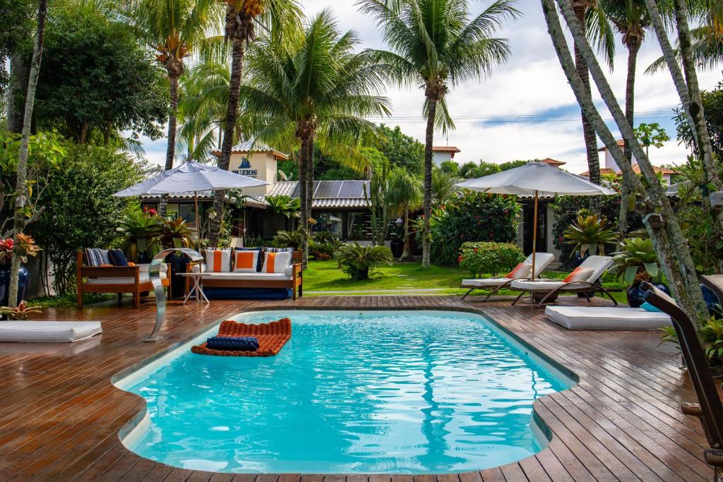 a pool at a resort with palm trees at Búzios House Oficial in Búzios