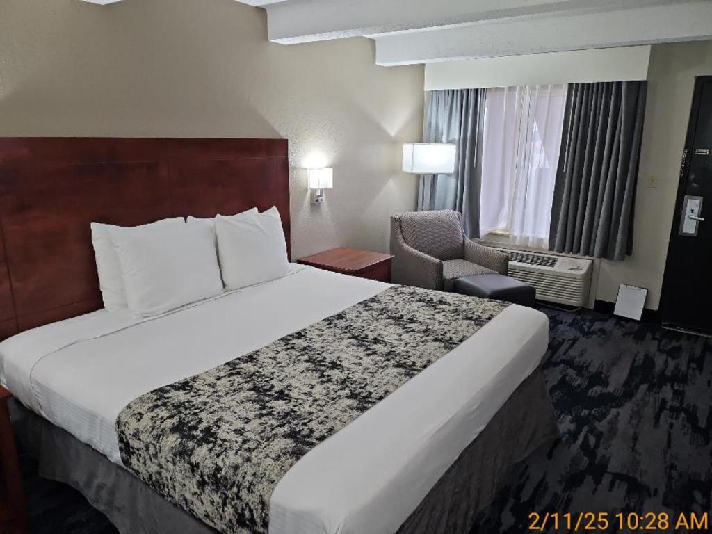 a hotel room with a large bed and a chair at Best Western Montis Inn in Saint Robert
