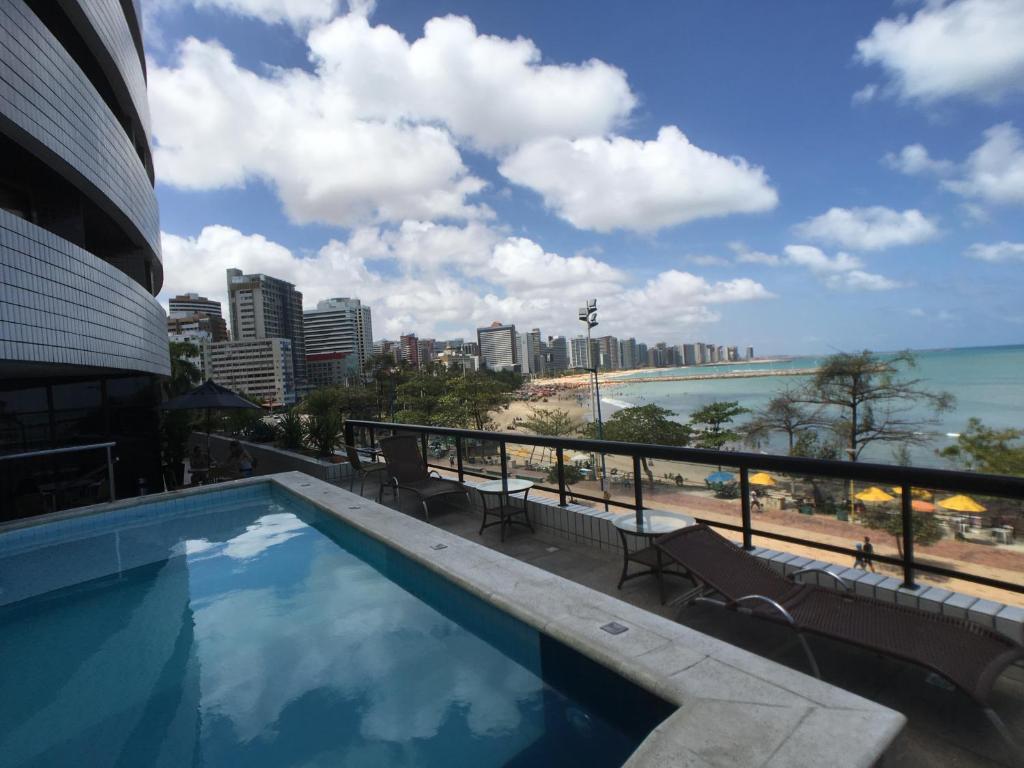 een zwembad met uitzicht op het strand en de gebouwen bij Beira Mar Suite in Fortaleza