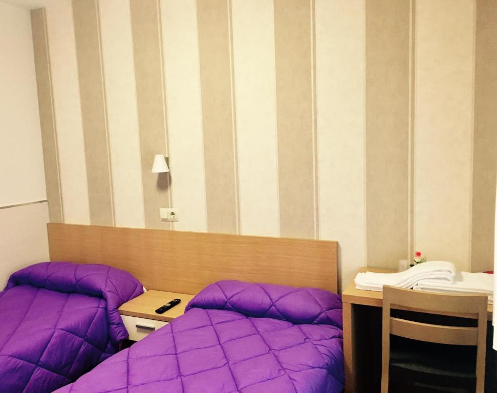 Habitación con almohadas moradas y escritorio con teléfono. en Hostal La Cortijana, en Logroño