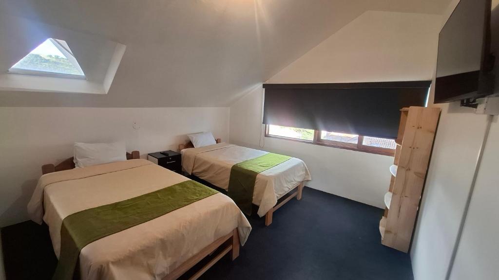 a small room with two beds and a window at Eco Bunnu Inn Santa Ana in Cusco