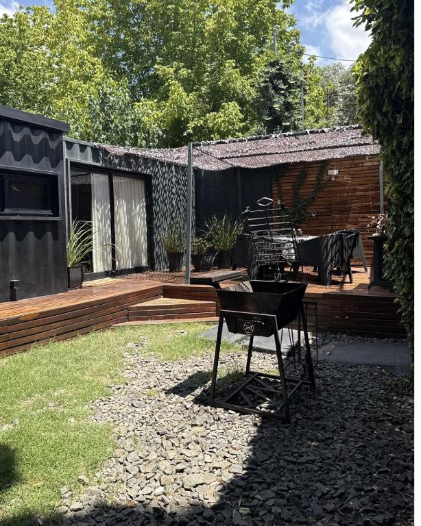 a backyard with a wooden deck with a table at Aromos Lodge- Chacras de Coria- in Ciudad Lujan de Cuyo