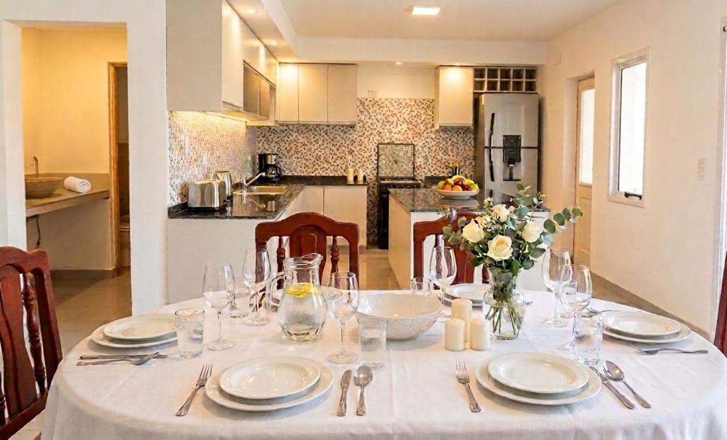 a dining table with a white table cloth and a kitchen at La soñada in Salta