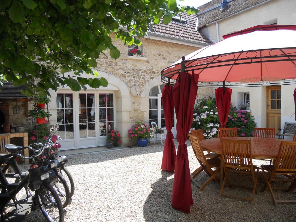 un patio con mesa y sombrilla en Les Mille et une Pierres en Mareuil-le-Port